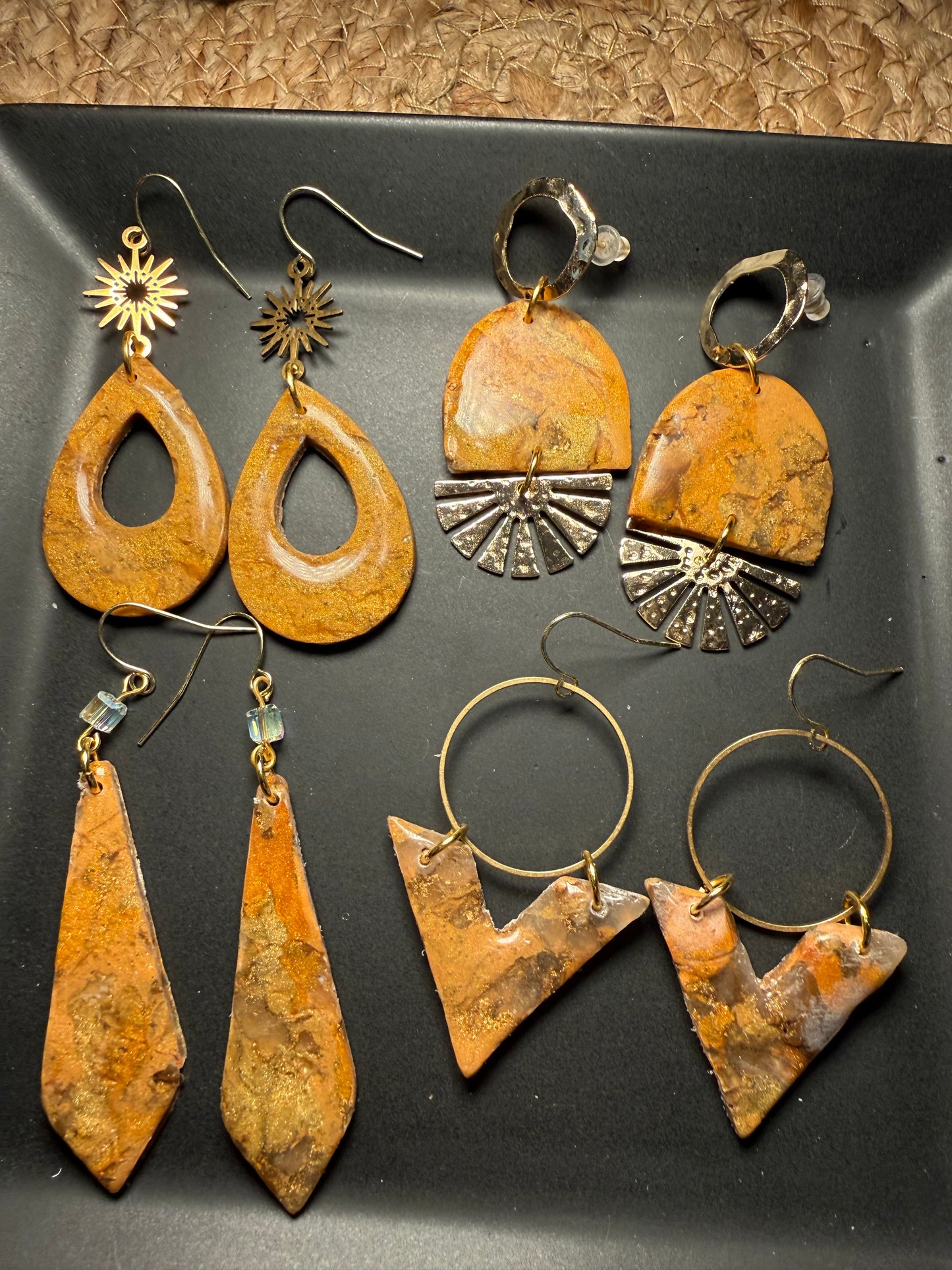 Collection of rustic gold and bronze earrings on a dark surface